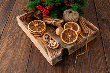 Dried orange slices, walnuts, cinnamon sticks, green spruce branches on a wooden podium and a rustic table. New year christmas concept. copy space