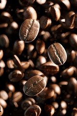 Brown roasted Arabica or Robusta coffee beans falling against a dark background