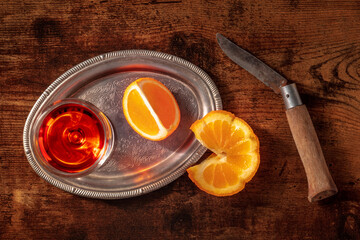 Sweet wine with a fresh orange on a dark rustic wooden background, on a vintage tray, overhead flat lay shot