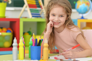 Portrait of cute girl drawing picture at home