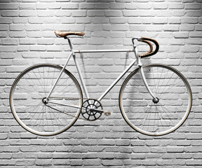 Retro style urban bicycle with a fixed gear hanging against a white brick wall