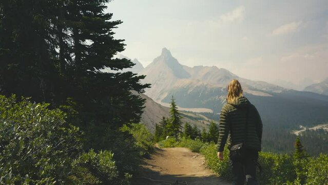 A cinematic clip of a women are hiking on a trail in the woods of Alberta, on the Parker Ridge Hike in Canada, over looking mountains and the stunning scenery of the Rocky Mountains in Canada