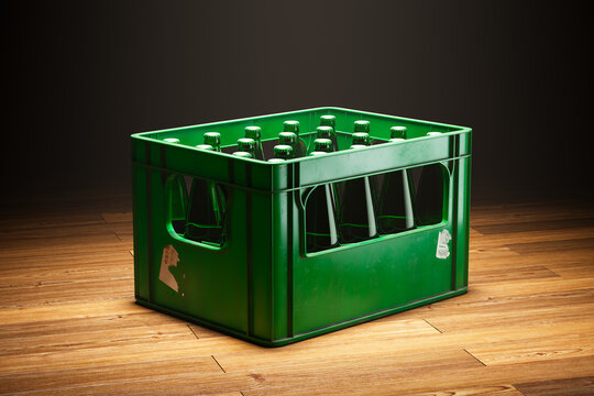 A green crate full of beer bottles standing in a spotlight on a wooden floor.