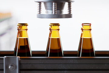 Glass bottles with liquid inside moving gradually in a factory pipeline. Beer