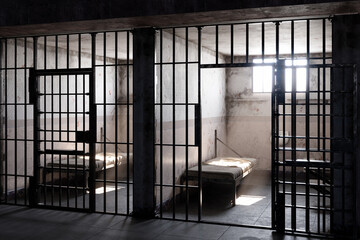 Sunlight streaming through window of empty prison cell, illuminating the bed