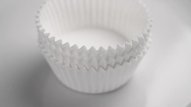 New white baking paper muffin cupcake cups close up. Stacking in slow motion close up