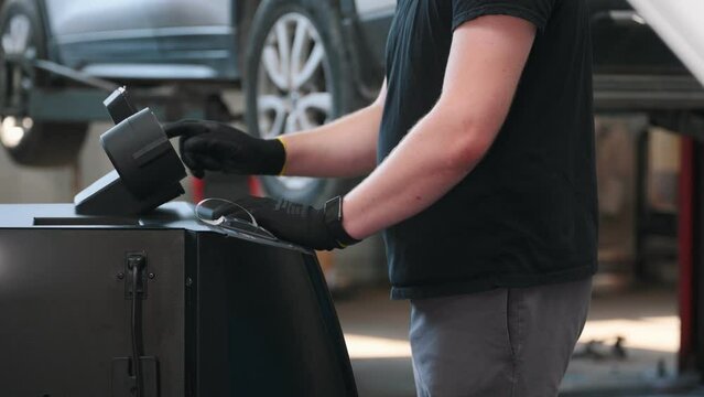 Car mechanic with manometer to fill the gas in the car air conditioning compressor. Service of checking the car air conditioner. Refrigerant recharge system.