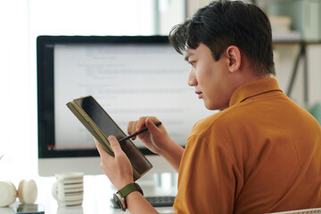 Serious young software developer testing application he created for tablet computer