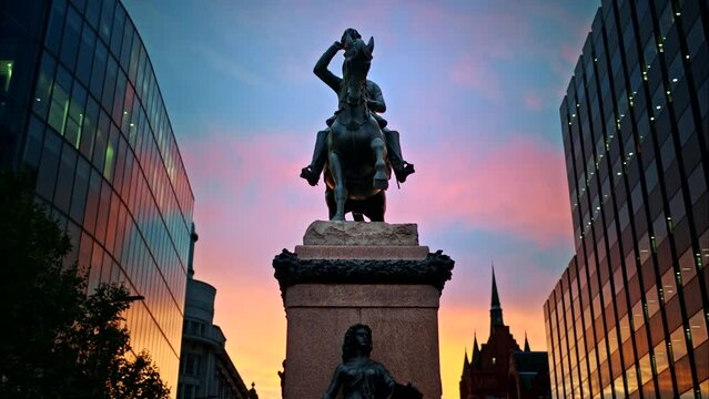 Prince Albert Equestrian Statue at sunset in London, United Kingdom. Modern buildings around, the sunset sky on the background
