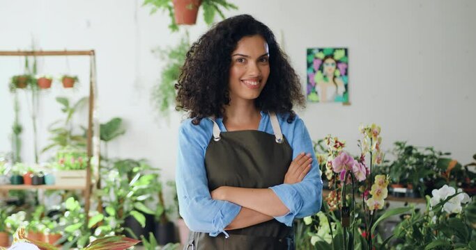 Portrait of african american woman florist business owner, smiling and looking at camera in a greenhouse. Gardener working in flower shop, plant store. Concept of floristry, retail small business and