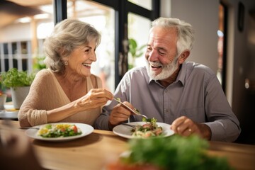 Food, retirement and a senior couple in an assisted living home while eating a meal for nutrition. Cute, love or smile with a happy elderly man feeding his wife in the dining room of a house - obrazy, fototapety, plakaty