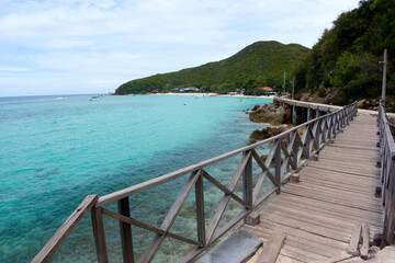 Seascape with a long wooden bridge and clear blue waters.