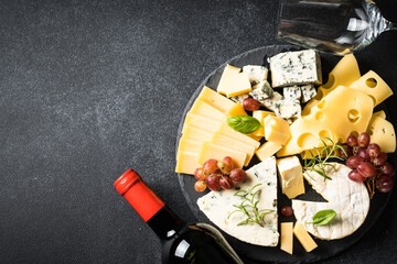 Obraz na płótnie Canvas Cheese platter and red wine at black background. Cheese assortment on slate board. Top view.
