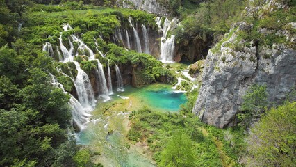 Beautiful waterfall in green forest, aerial top down view. Summer mountain landscape. Famous landmark and tourist attraction.