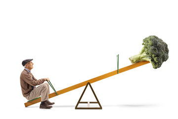 Full length profile shot of an elderly man and a broccoli on a seesaw
