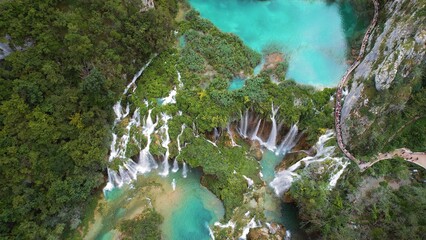 Waterfall and river streams flowing down. Aerial top down view of lush green cliff in dense mountain forest. Spring water.