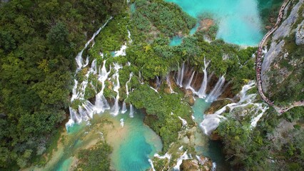 High waterfall and river streams flowing and falling down. Aerial top down view of lush green cliff...
