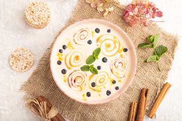 Yoghurt with bilberry and caramel in ceramic bowl on gray concrete, top view.