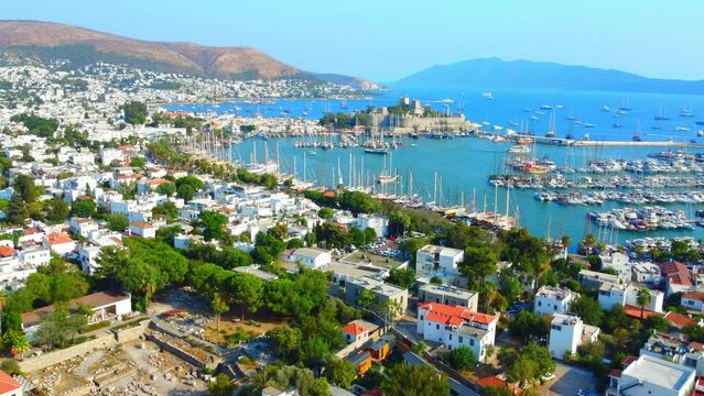 Aerial view of large tourist city of Bodrum in Turkey from drone, view of bay, yachts, boats. Against backdrop of mountains and azure and turquoise blue water. Resort in south of sea. Yachting sport