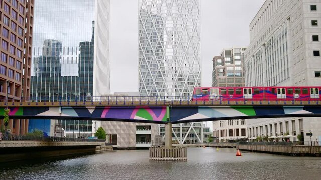 Street scape of the Canary Wharf district, water channels with train moving on a bridge, skyscrapers around in London, United Kingdom
