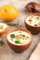 Yoghurt with granadilla and mint in clay bowl on brown concrete, side view, selective focus