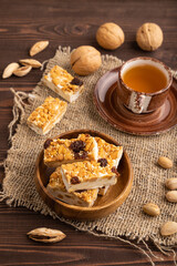 Traditional candy nougat with nuts and sesame on brown wooden, side view.