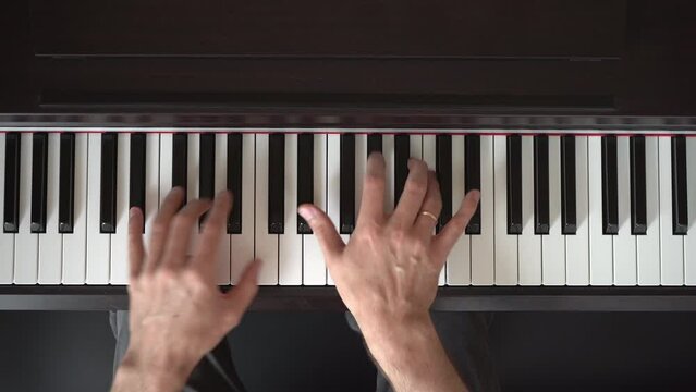 A male pianist plays at home on the keyboard of a digital electronic piano. Home piano lessons.