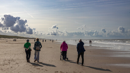People walk on the beach along the North Sea with a beautiful sky in September