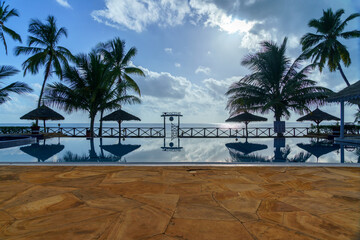 seaside resort swiming pool with silhoutted entrance against a clouded blue sky