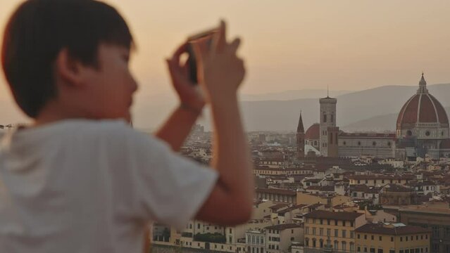 Cathedral of Saint Mary of the Flower at sunrise or sunset, Italy, Florence. Tourist boy taking pictures of picturesque golden sunset city landscape on smartphone. Tourism, holidays, vacation concept.
