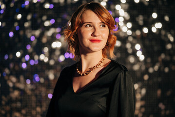 Young attractive woman celebrating party redhead black dress sparkling background night portrait in...
