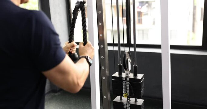 Athlete shaking muscles of arms with help of simulator with ropes closeup 4k movie slow motion. Regular sports training concept