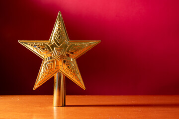 golden christmas star on wooden table and red background