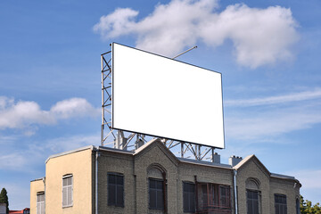 Large outdoor advertising billboard on the roof of an old brick building.