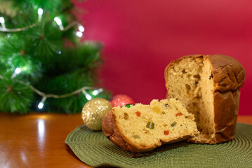 Panettone, Italian sweet bread with dried fruits, on blurred red Christmas background