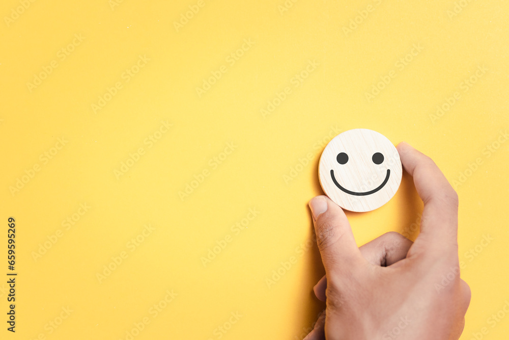 Poster customer satisfaction service concept. hand holding wooden block with a smiley face icon to rate sat