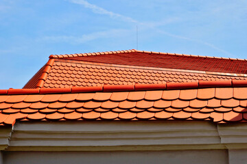 beavertail clay tile sloped residential roofs. half round ridge tiles. new construction. closeup view. blue sky and white clouds. modern house architecture. 