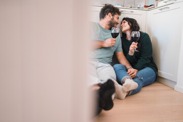 Young Couple Toasting in New Home - A young casual-dressed couple, in their 30s, toast with wine glasses in their new kitchen. Lovingly gaze into each other's eyes.