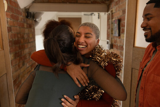 Friend arriving at a christmas party giving a big hug to the host