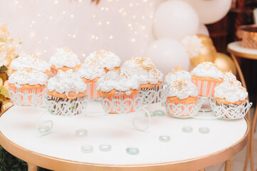 Cupcakes con glaseado blanco con perlas sobre mesa blanca y fondo de fiesta 