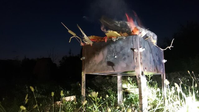 Fire burns in the barbecue at night
