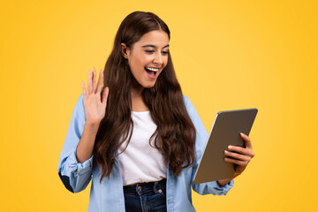 Naklejka premium Smiling pretty european woman student, use tablet, waving hand