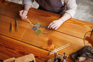 Top view of florist pouring dried flowers on grass for herbarium in floral shop
