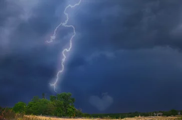 Fotobehang lightning on a dark sky. Thunderstorm, a heart-shaped cloud in the sky during a thunderstorm. lightning in the field © Варвара Гиделюк