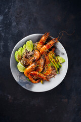 Traditional Thai fried king prawns with Asian vegetable, avocado slices and rice served as top view on a design plate with text space
