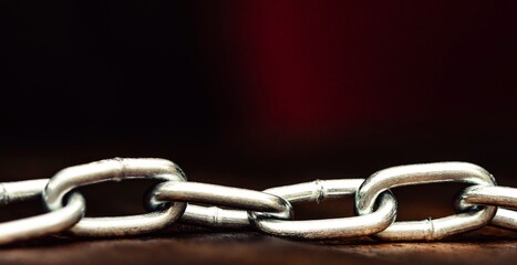 Metal shiny chain on a wooden surface close-up