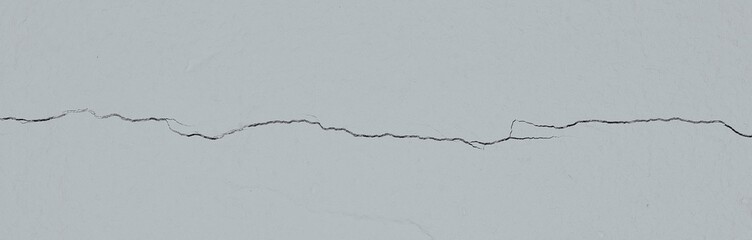 A crack in the gray wall. Cracked surface