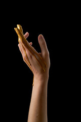 Fototapeta premium Female hand in liquid gold on a black background.