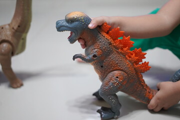 Young Asian man plays with colorful dinosaur toys at home. Little child in the house is playing with toys on the floor. Children's toys. Dinosaurs. Children like it. Dinosaur toys.