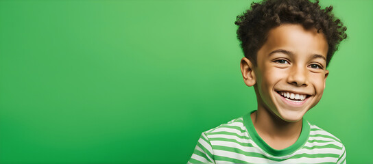 Excited smiling boy on solid green background - obrazy, fototapety, plakaty